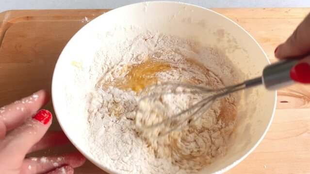 Add flour to the dough, sift and mix well in a white bowl on a wooden background. Step 4.
