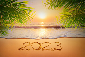 Welcoming The year 2023 handwriting on sand beach and coconut leaf, Happy New Year coming...