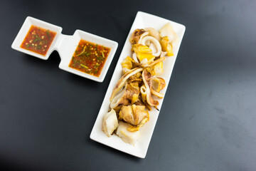 Grilled squid grilled over a charcoal grill eaten with seafood sauce, a popular street food in Thailand.