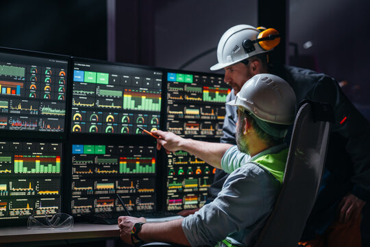 Group of engenners following production line using computer screens with Industry 4.0. Couple of factory operators controll assembly line using screens with human-machine interface