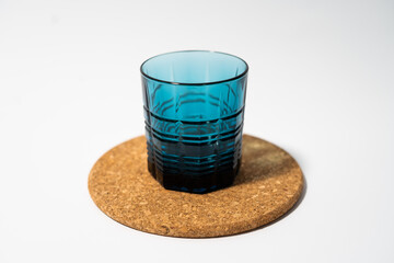 Blue glass cups for whiskey and any drink on a cork stand on a white background