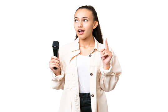 Young singer woman picking up a microphone over isolated chroma key background thinking an idea pointing the finger up