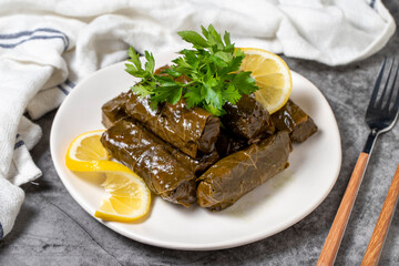 Stuffed leaves with olive oil or dolma on a dark background. Turkish cuisine appetizer flavors....
