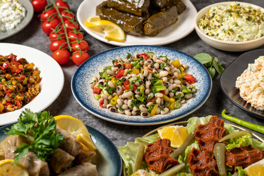 Traditional Turkish and Greek dinner appetizer table. Mediterranean appetizer concept. Dry cowpea salad, roasted eggplant salad, stuffed leaves with olive oil, stuffed dried peppers, cabbage rolls