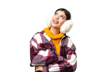 Young Russian woman wearing winter muffs over isolated chroma key background looking up while smiling