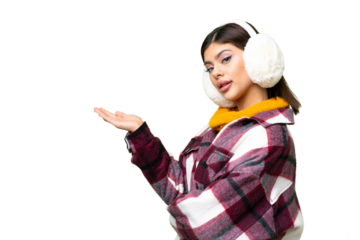 Young Russian woman wearing winter muffs over isolated chroma key background extending hands to the side for inviting to come