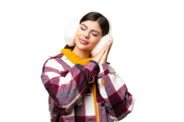 Young Russian woman wearing winter muffs over isolated chroma key background making sleep gesture in dorable expression