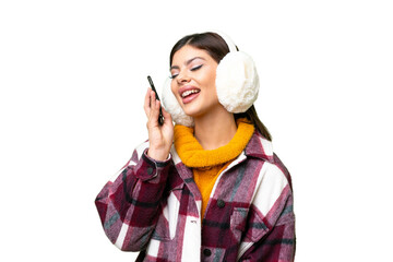 Young Russian woman wearing winter muffs over isolated chroma key background keeping a conversation...