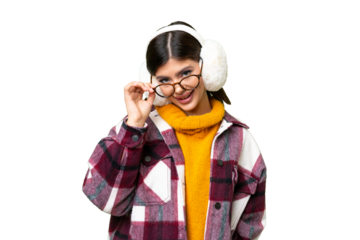 Young Russian woman wearing winter muffs over isolated chroma key background with glasses and happy