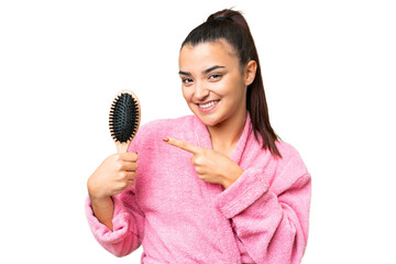 Young woman in a bathrobe with hair comb over isolated chroma key background and pointing it