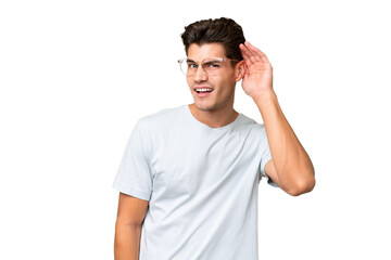 Obraz premium Young caucasian handsome man over isolated background listening to something by putting hand on the ear