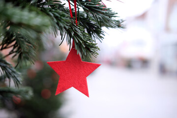 Nahaufnahme eines roten Weihnachtssterns aus Filz an einer weihnachtlich geschmückten Tanne in...