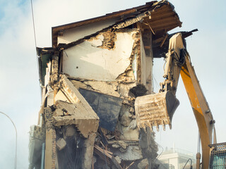 Fototapeta premium Process of demolition of civil building dismantling. Excavator breaking walls. renovation of the housing stock