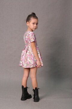 little girl in summer printed dress and combat boots full body photo on gray background