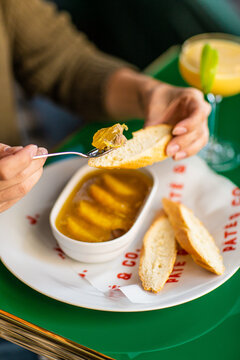 Girl smears chicken pate with a fork on bread