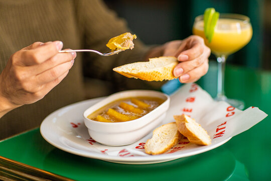 Girl smears chicken pate with a fork on bread