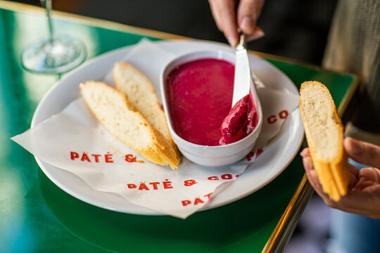 Girl with a knife smears beetroot pate on bread