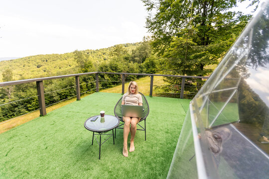 woman working on laptop Outdoor Bubble Tent House Dome - Nature travel Concept.
