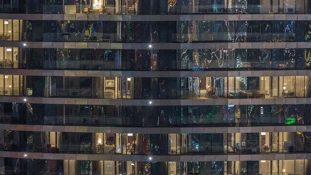 Outside view of windows in apartments of a high class building at night timelapse. Glowing yellow lights in skyscraper