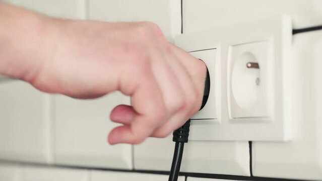 Human hand plugging cable to socket for electricity connection. Safe voltage usage from energy network