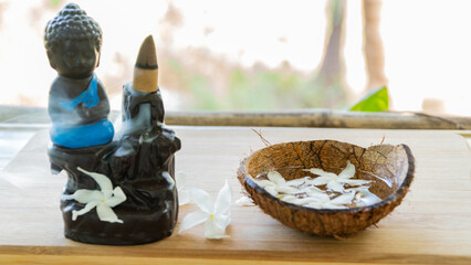 Steaming incense on a Buddha figurine with floral decoration, oriental traditions