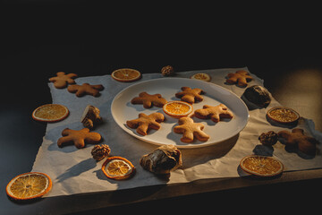 Gingerbread men with orange and nuts on baking paper . Christmas wallpaper.