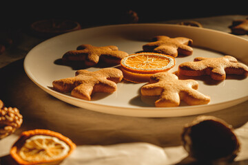 Gingerbread men with orange and nuts on baking paper . Christmas wallpaper.