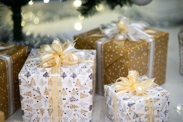 Fototapeta na wymiar Close-up of beautiful wrapped gifts under Christmas tree. White and golden colors.