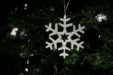 Close-up of silver sparkling Christmas tree ornament in shape of snowflake star with glitter,...