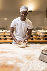 smiling young black man working in a bread factory, learning the trade.