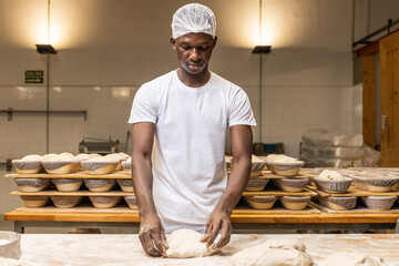 young black man working in a bread factory, learning the trade.