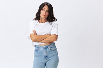 Woman in white t-shirt on white background brunette hands up gestures and signals poses in jeans emotion, lifestyle smiles, copy space