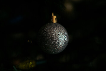 Moody image of sparkling silver Christmas tree ball ornament with glitter on dark background, selective focus macro shot for holiday or christmas card - 552796102