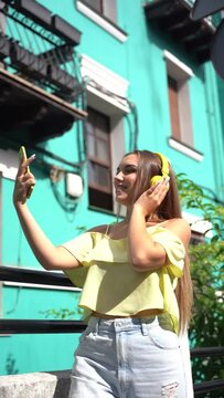 Summer lifestyle, blonde woman in a house with a green colorful facade listening to music