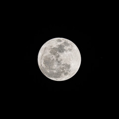 Beautiful soft white super full moon with details on the lunar surface in the dark night isolated on black sky background