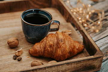 Fresh delicious croissant and espresso on wooden table with lights