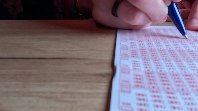 Picking lotto numbers.
Lottery playing cards. A woman's hand crosses out the numbers.
