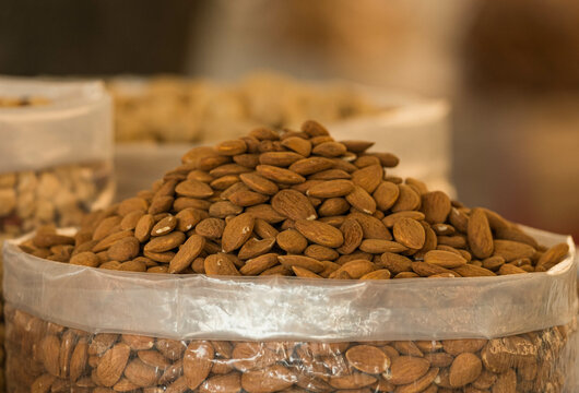 At the market a stack of almonds in a plastic bag. Beautiful raw food for vegan people. A mountain of almonds ready to be bought. Vegetal food. Healthy food.
