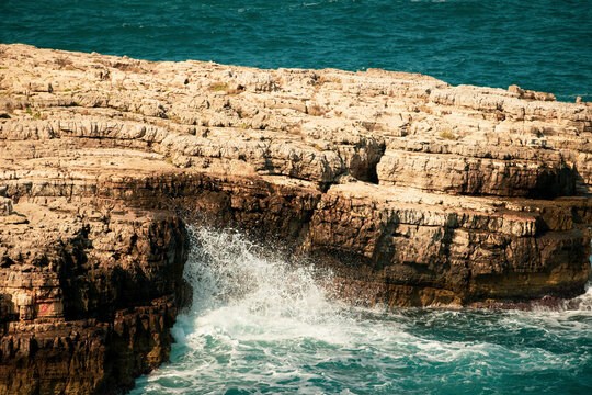 Cliff hit by sea waves in the summer. Beautiful holiday destination on mediterranean country. Best Italy location. Blue of the sea near old cliffs.
