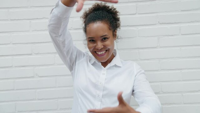 African american woman smiling confident doing photo gesture with hands over isolated white brick background