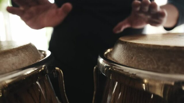 Man hands playing on kongo drums in recording studio, close up view. Guy making rhythm on traditional ethnic african folk music instruments