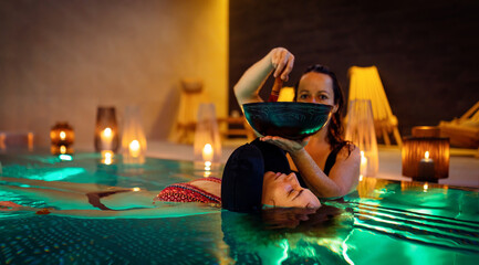 Therapeutic exercise in the pool. Woman receiving an aquatic therapy in the pool. Water relaxation. Music therapy and deep meditation.