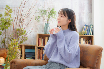 飲み物を手にホッとする若い女性