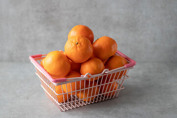 Tangerines in a metal basket on a gray background.