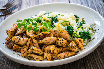 Fried chicken nuggets with white rice and spinach on wooden table
