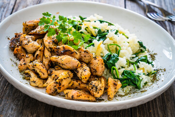 Fried chicken nuggets with white rice and spinach on wooden table
