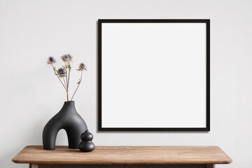 Empty square frame mockup in modern minimalist interior with plant in trendy vase on white wall...