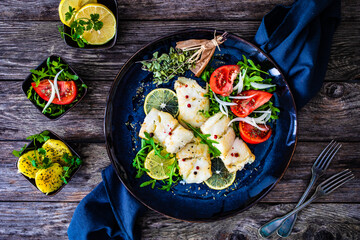 Fish dish - fried halibut with boiled potatoes and fresh vegetables on wooden table