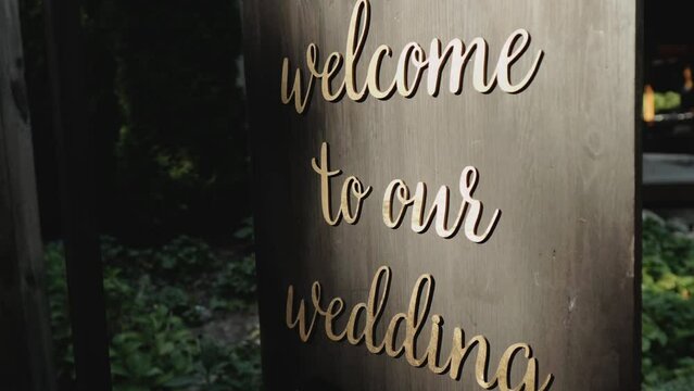 Wooden board with message Welcome to our wedding, slow motion shot.