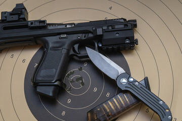 Tactical equipment, a folding knife, a modern pistol with a red dot sight and a target for shooting.